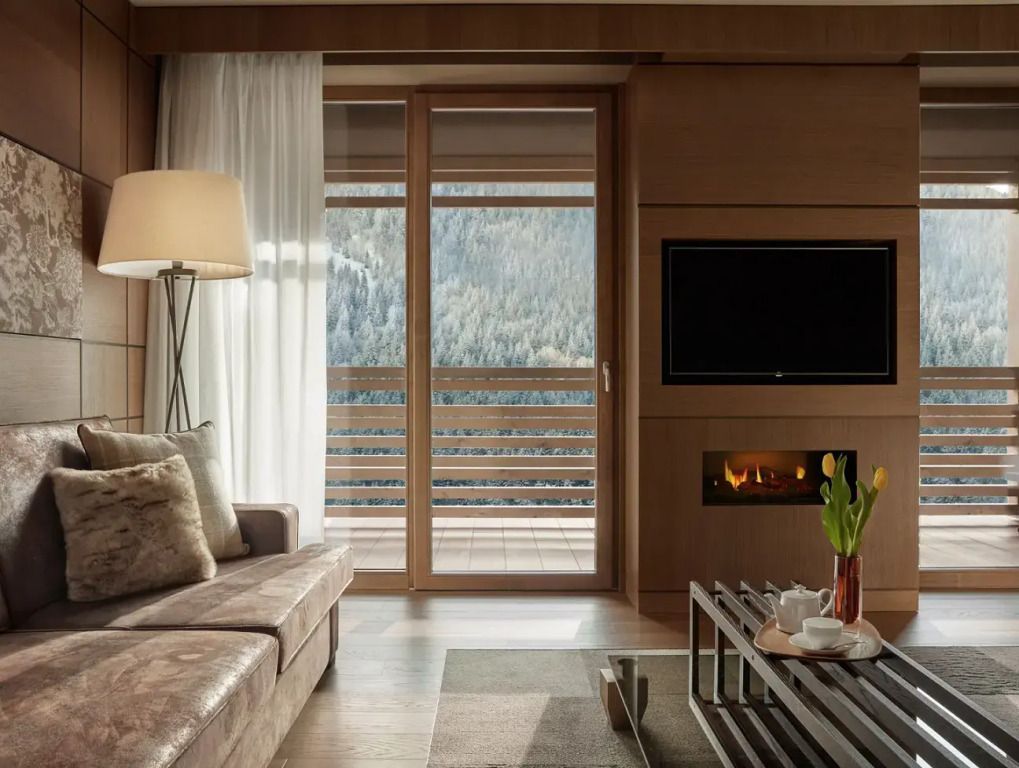 Wohnzimmer mit Kamin, Sofas, Tisch und Bergblick im Lefay Resort Dolomiti