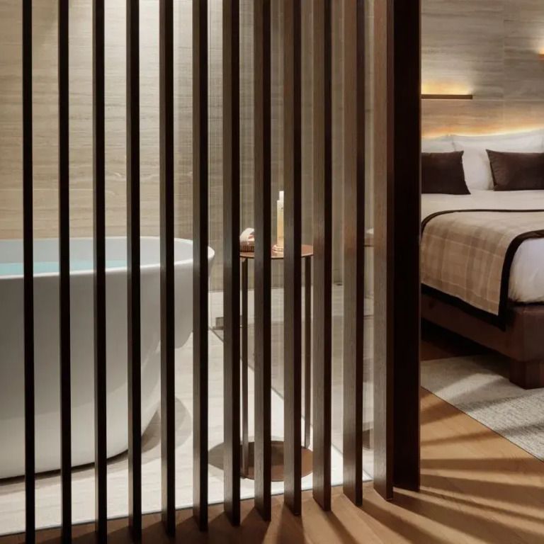 Moderne Suite mit freistehender Badewanne und Doppelbett, durch Holzlatten getrennt.