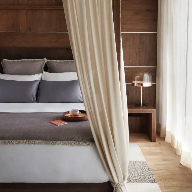 Elegantes Schlafzimmer mit Doppelbett, Kissen und Vorhängen, warmes Holzdesign