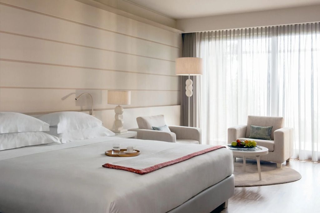 Elegantes Zimmer mit Doppelbett, Sitzbereich und großen Fenstern mit Vorhängen