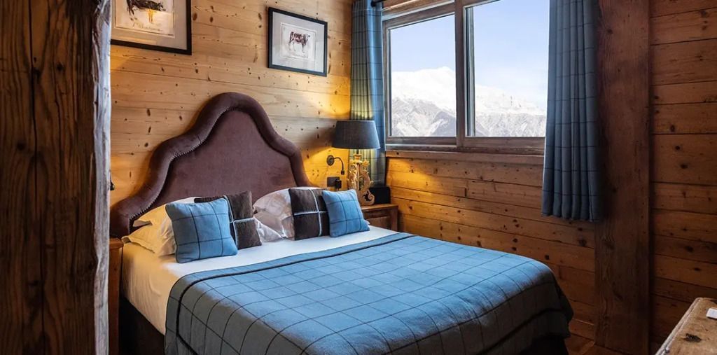 Gemütliches Schlafzimmer mit Holzwänden und Bergblick in einem Chalet