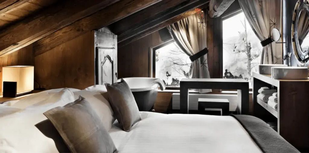 Elegantes Schlafzimmer im Dachgeschoss mit freistehender Badewanne und Bergblick.