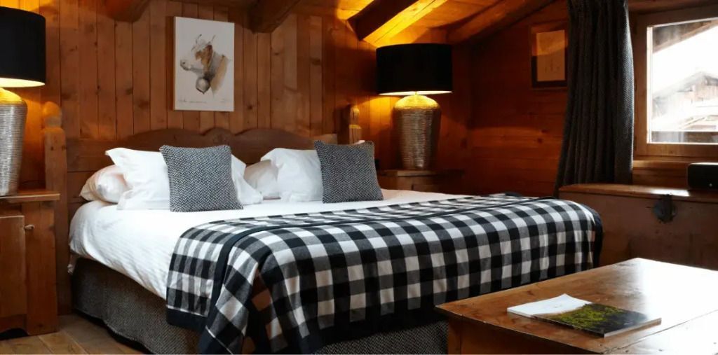 Gemütliches Schlafzimmer mit kariertem Bettbezug in rustikalem Alpenstil
