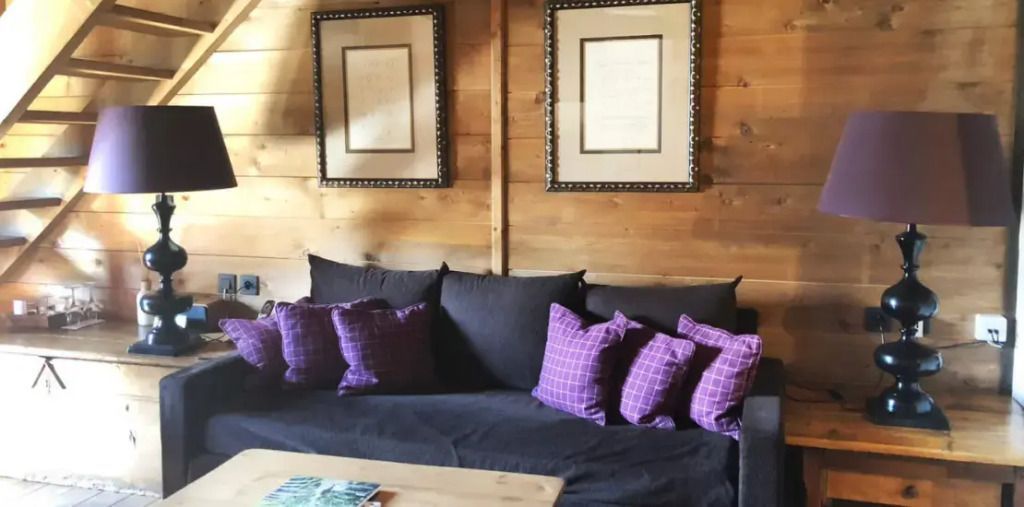 Sofa mit lila Kissen in rustikalem Zimmer mit Holzwänden
