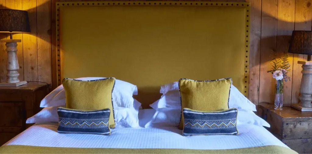 Bett mit gelbem Hintergrund und dekorativen Kissen