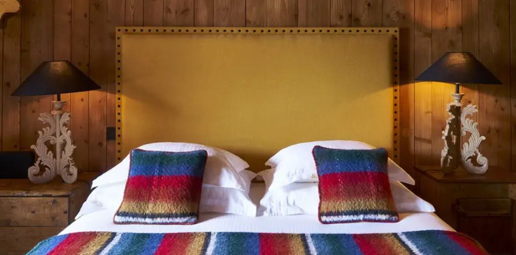 Doppelbett mit bunten Streifenkissen und Holzwand