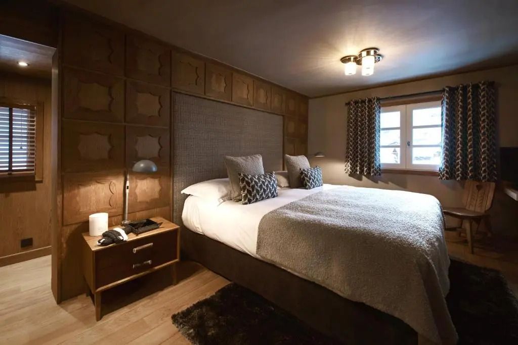 Gemütliches Schlafzimmer mit Holzwänden und großem Bett im Les Fermes De Marie.