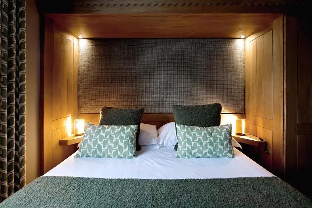Kuscheliges Doppelbett mit weichen Polstern und warmem Beleuchtung im Chalet-Stil.