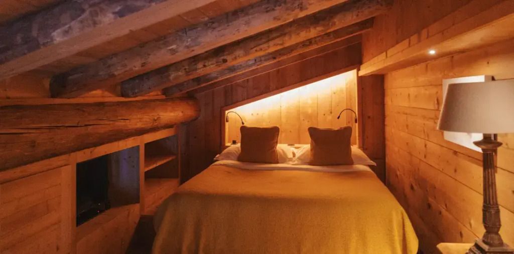 Gemütliches Schlafzimmer unter Holzgebälk mit sepiafarbener Beleuchtung