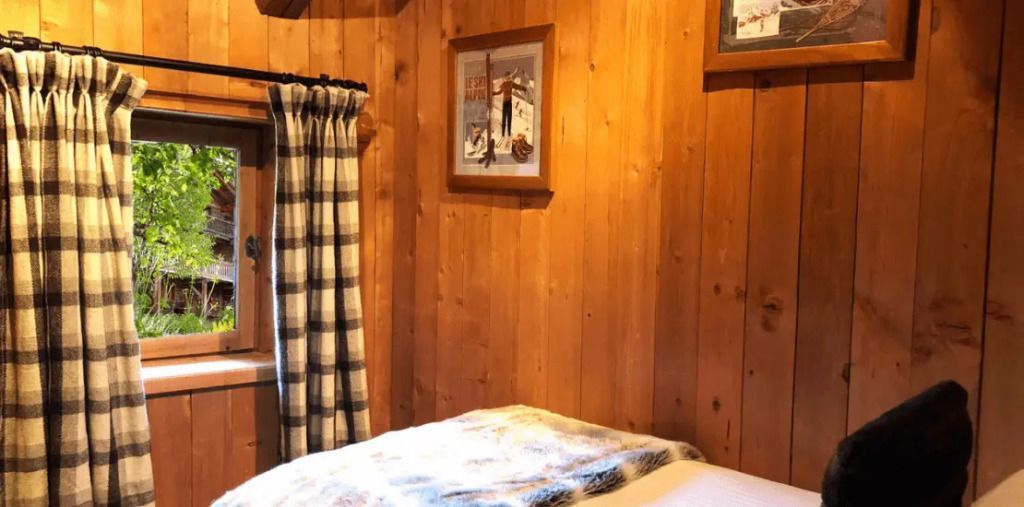 Gemütlicher Raum mit Holzwänden und karierten Vorhängen in der Mont Joly Suite.