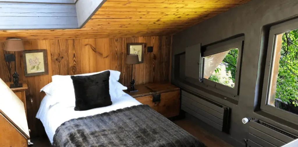 Einzelbett mit dunkler Bettwäsche unter einer Dachschräge in der Mont Joly Suite.