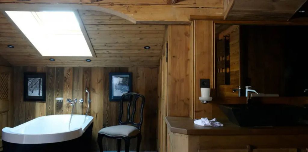 Gemütliche Holzausstattung im Badezimmer der Mont Joly Suite mit Dachfenster.