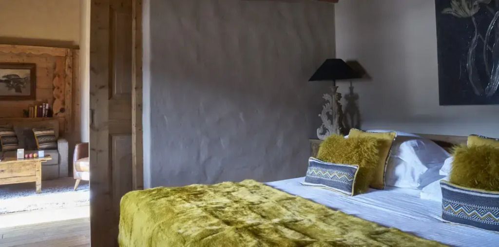 Gemütliches Bett mit gelber Decke und dekorativen Kissen in der Prestige Doppel Suite