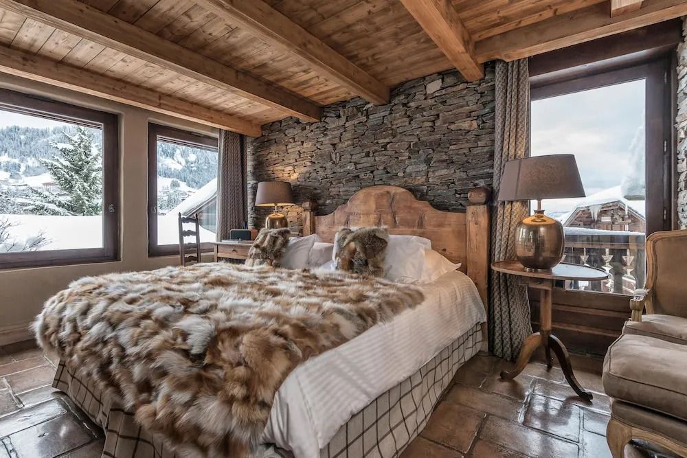 Rustikales Schlafzimmer mit Holzbalkendecke und Fellüberwurf im Les Fermes De Marie Hotel