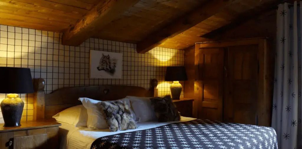 Gemütliches Chalet-Schlafzimmer mit Holzbalkendecke und stimmungsvoller Beleuchtung