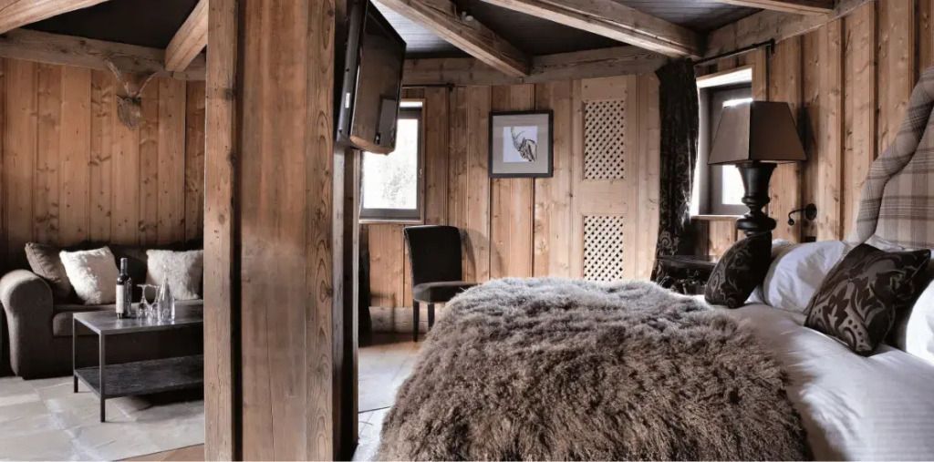 Rustikales Zimmer mit Holzwänden und gemütlichem Bett mit flauschiger Decke