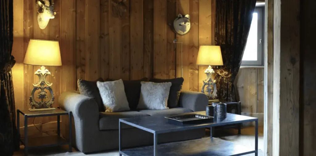 Gemütliche Sitzecke mit Sofa, Lampe und Holzwänden im Chalet-Stil