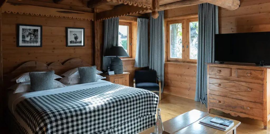 Gemütliches Schlafzimmer in rustikalem Holzinterieur mit großen Fenstern.