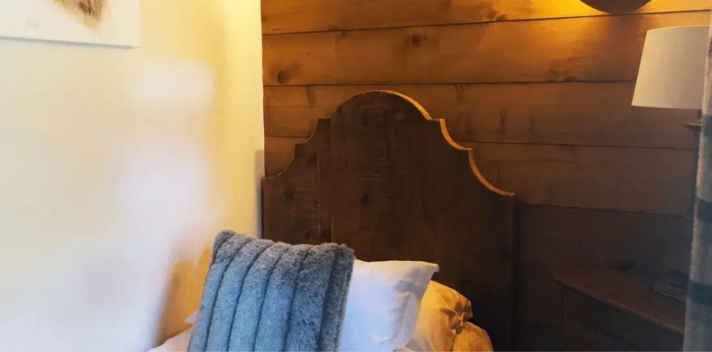 Detailaufnahme eines Bettes mit Holz-Kopfteil und flauschiger Decke im Superior-Familienzimmer