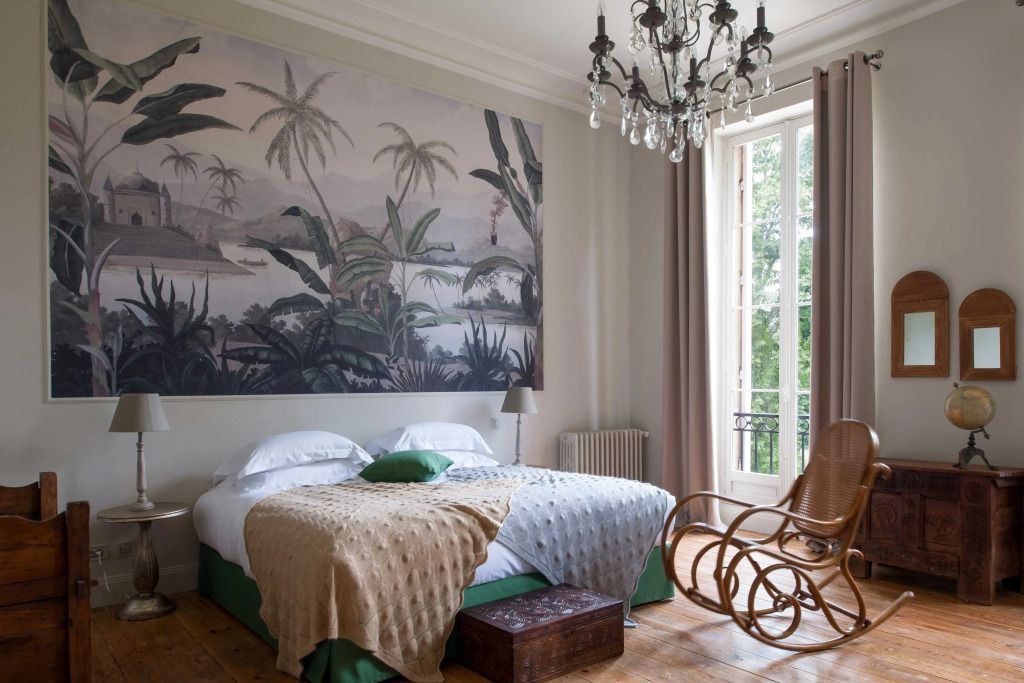 Elegant eingerichtetes Schlafzimmer mit Doppelbett und Wandgemälde mit tropischen Pflanzen.