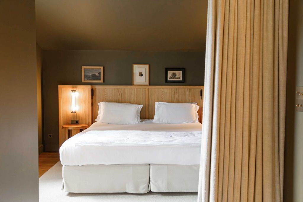 Gemütliches Schlafzimmer mit Doppelbett, Holzkopfteil und Kunst an der Wand