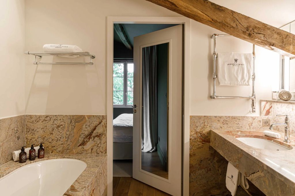 Badezimmer mit hellem Marmor und Blick in das Schlafzimmer