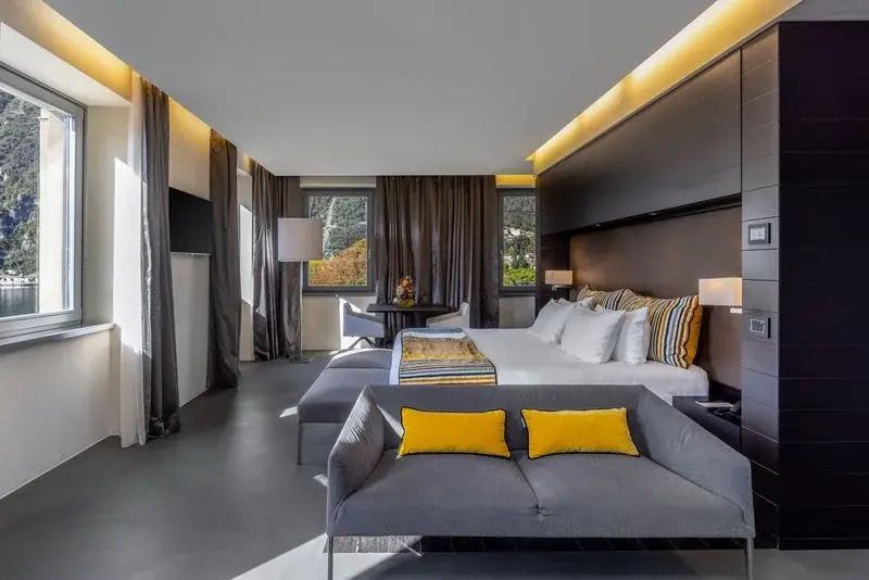 Moderne Junior-Suite mit Doppelbett, Sofaecke und großem Fenster mit Seeblick.