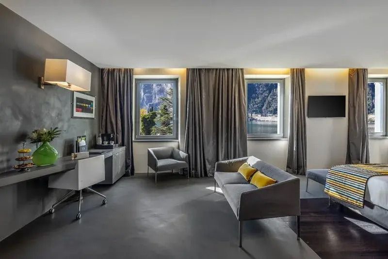 Geräumige Junior-Suite mit Schreibtisch, Sofa und zwei Fenstern mit Seeblick.