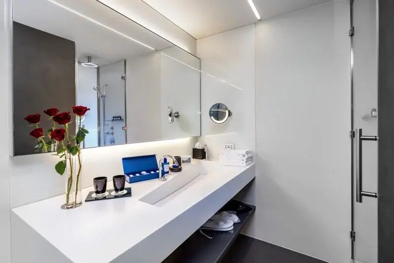 Modernes Badezimmer mit großem Spiegel, Blumen und eleganter Waschtischfläche.