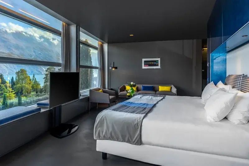 Modernes Doppelzimmer mit großem Bett und Panoramafenstern mit Parkblick
