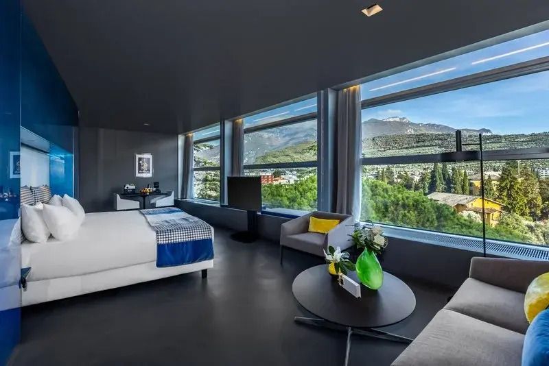 Lichtdurchflutetes Zimmer mit Doppelbett und Panoramafenstern mit Berg- und Parkblick