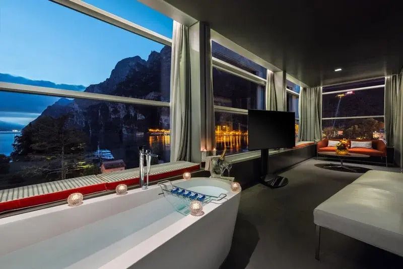Moderne Suite mit Panorama-Seeblick und luxuriöser Badewanne bei Nacht