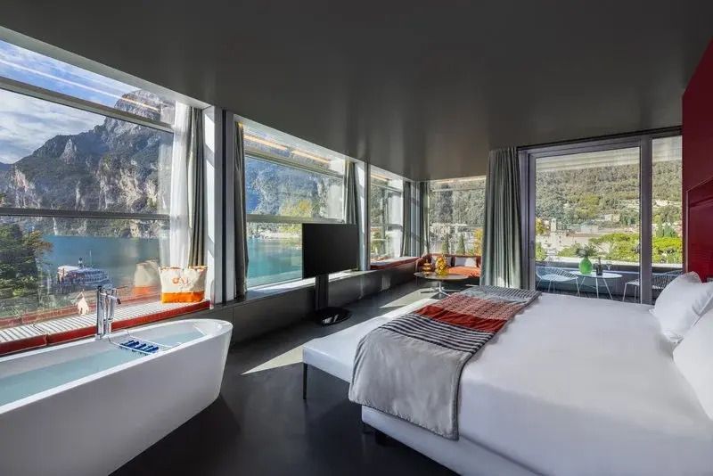 Elegante Suite mit Blick auf See und Berge durch große Fenster