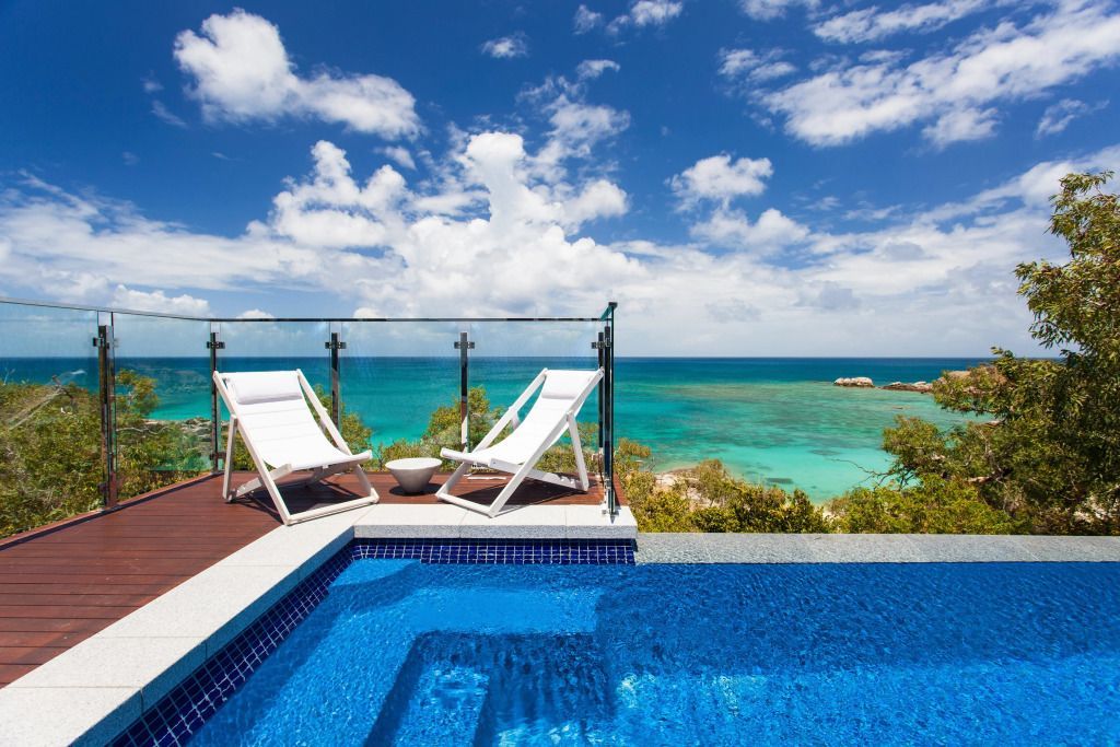 Terrasse mit Liegestühlen und Blick auf türkisblaues Meer