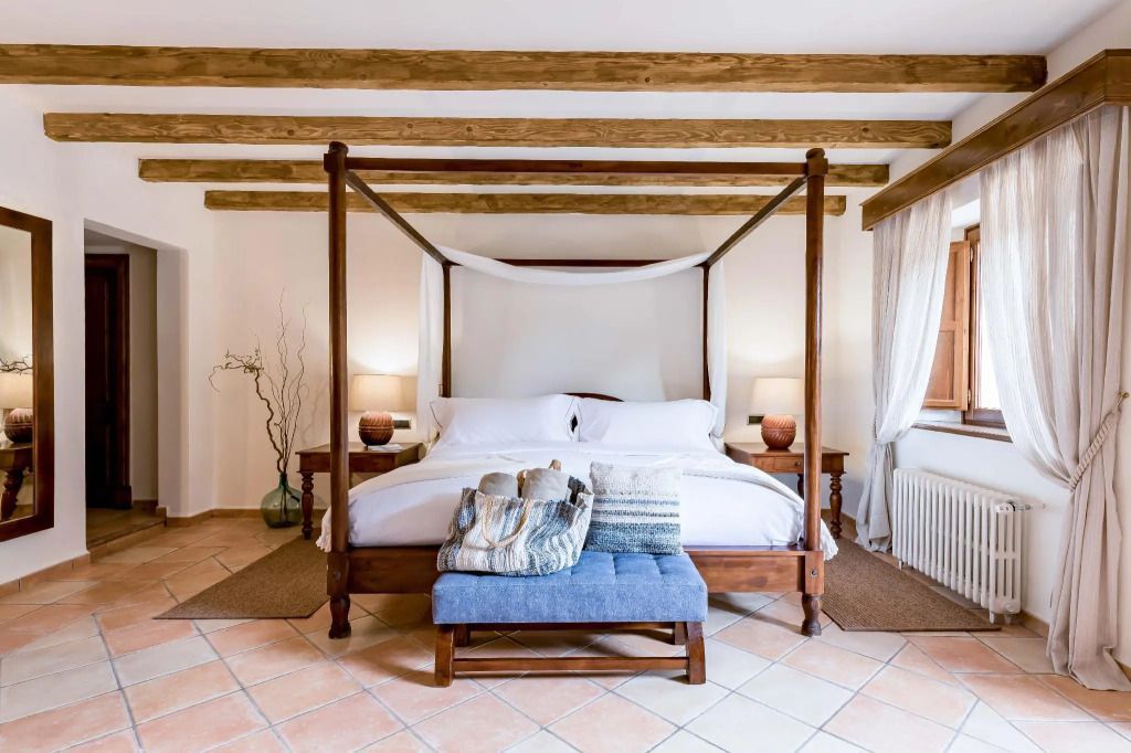 Rustikales Deluxe-Zimmer mit Himmelbett und Holzbalkendecke.