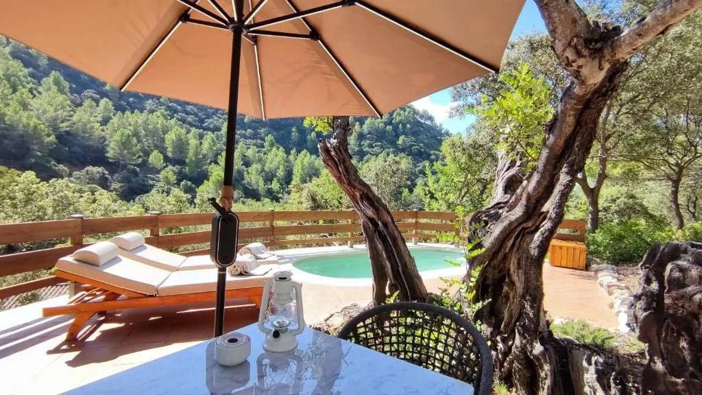 Terrasse mit Esstisch und Blick auf Pool und grüne Landschaft