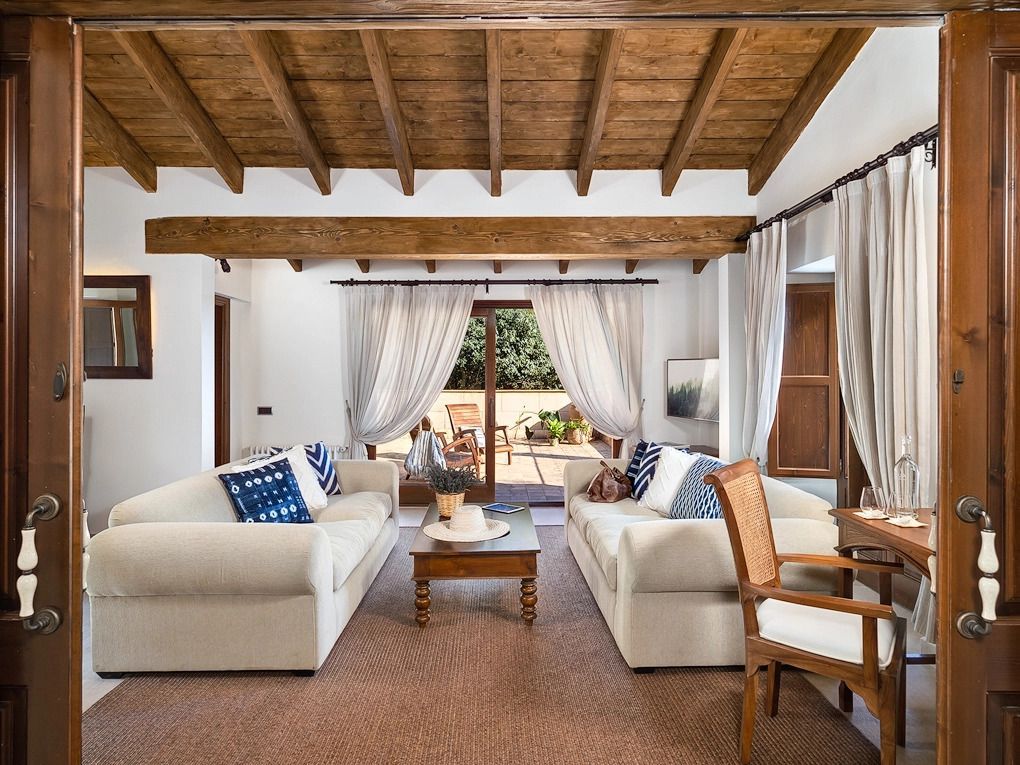 Elegantes Wohnzimmer einer Suite mit Holzbalkendecke und zwei Sofas vor einem großen Fenster