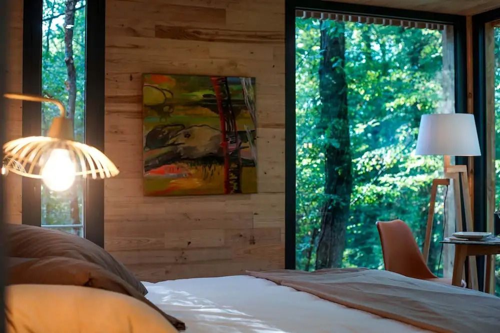 Zimmer mit Blick auf den Wald durch große Fenster und moderne Kunst an der Wand