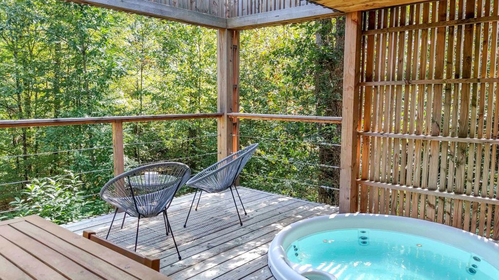 Holzterrasse mit Jacuzzi und stilvollen Sitzgelegenheiten, umgeben von üppigem Grün