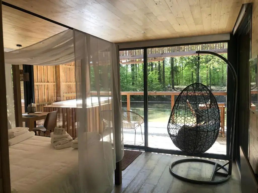 Suite mit Hängesessel und großer Fensterfront zur Terrasse mit Waldblick