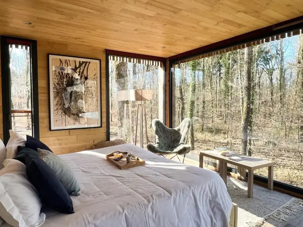 Gemütliches Zimmer mit großem Bett und Panoramafenstern zur Natur