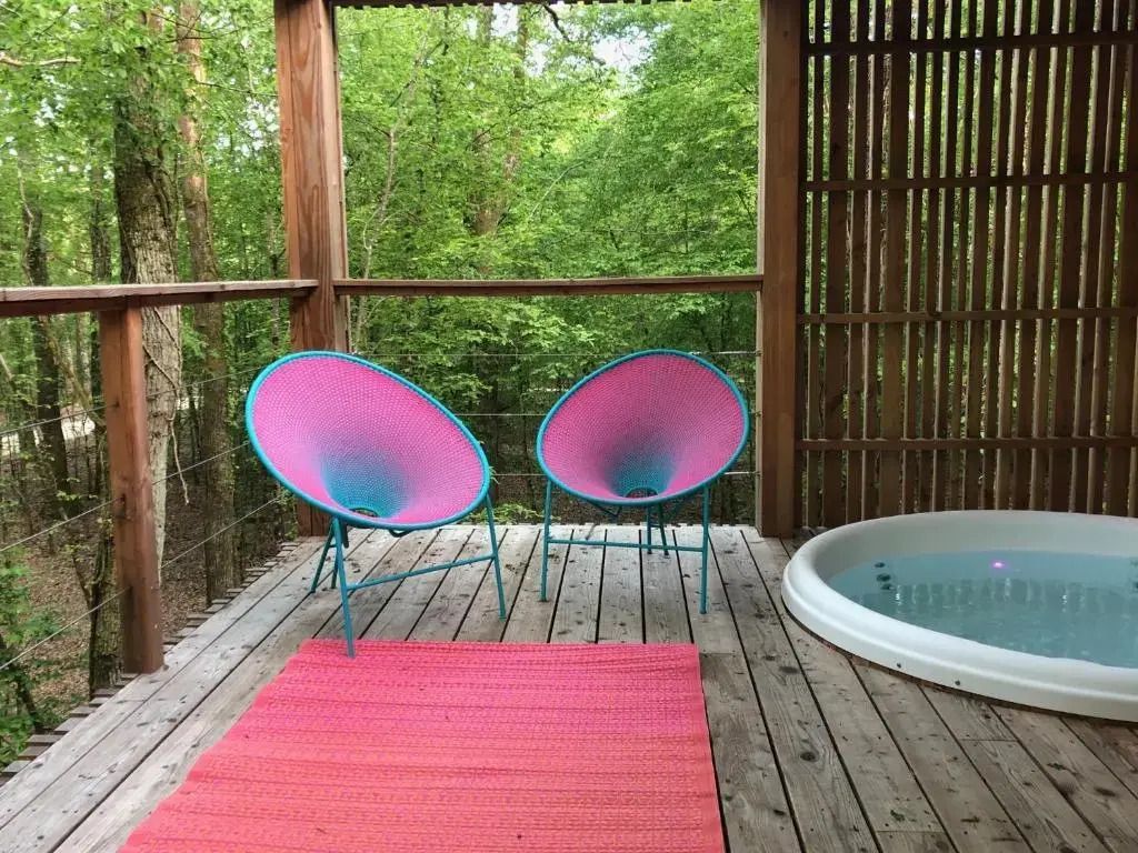 Farbenfrohe Terrasse mit bunten Stühlen und Whirlpool im Grünen