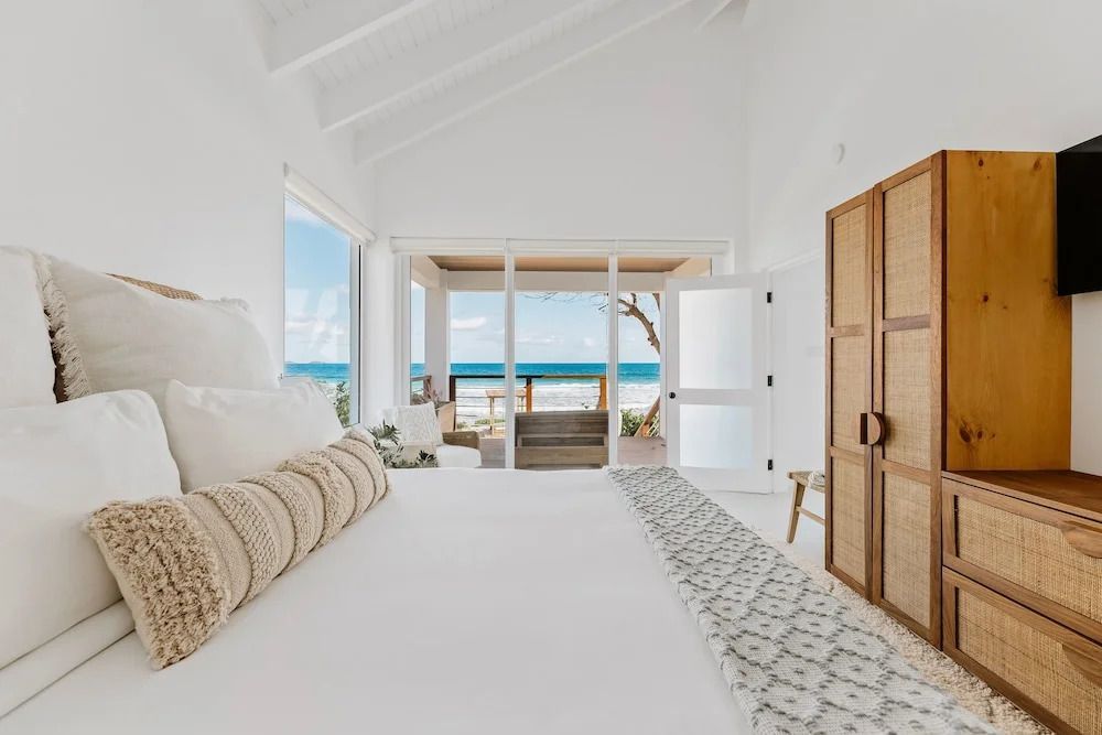 Schlafzimmer mit Balkon und Ausblick auf den Ozean, helle Einrichtung