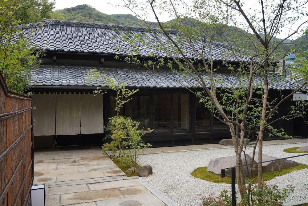 Außenansicht eines japanischen Gebäudes mit grüner Umgebung und Steinweg