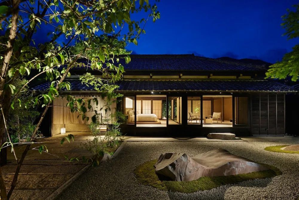 Beleuchteter Gartenbereich vor einem japanischen Gebäude bei Nacht