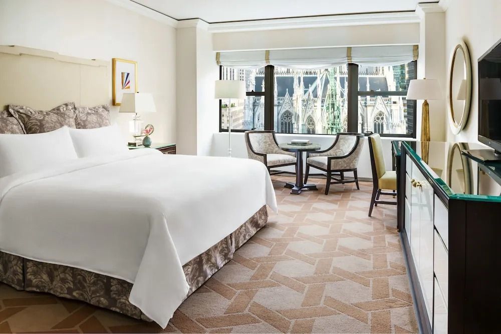 Hotelzimmer mit Doppelbett und Tisch vor einem Fenster mit Blick auf die Kathedrale.