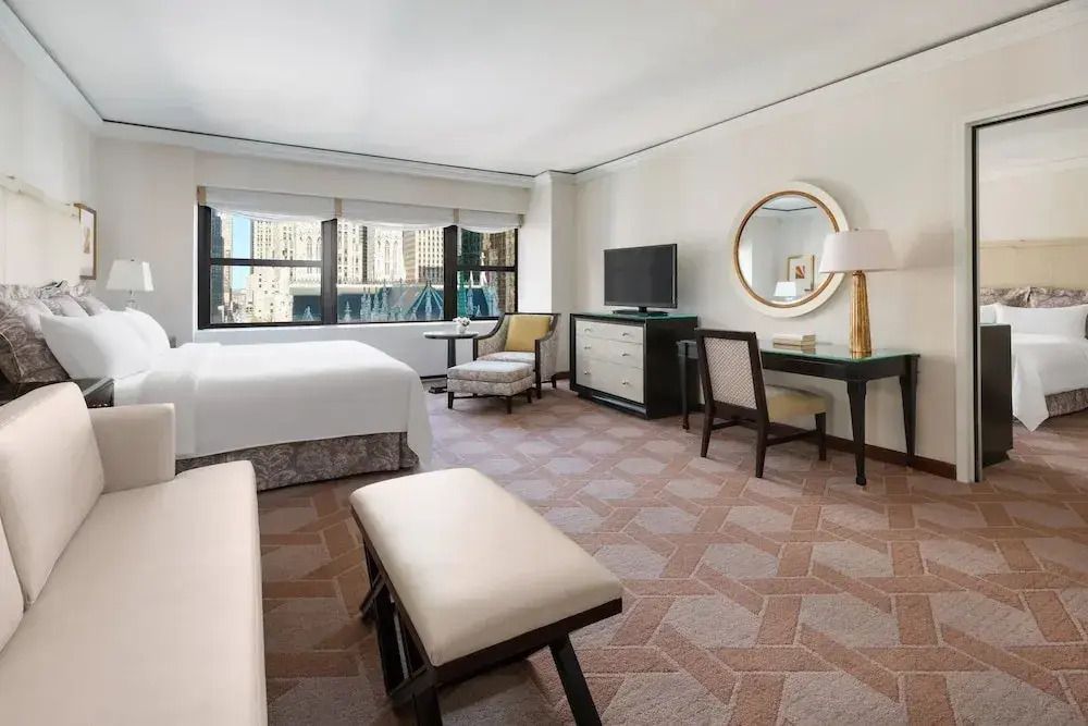 Geräumiges Hotelzimmer mit moderner Einrichtung und runder Spiegel an der Wand.