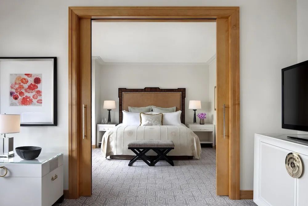 Elegantes Schlafzimmer mit Kingsize-Bett und klassischer Holztür im Lotte New York Palace