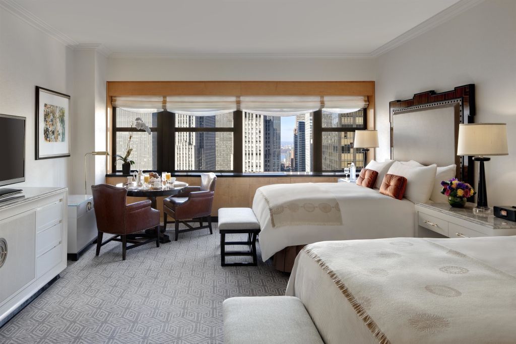 Geräumiges Hotelzimmer mit Blick auf die Skyline von New York und zwei großen Betten.