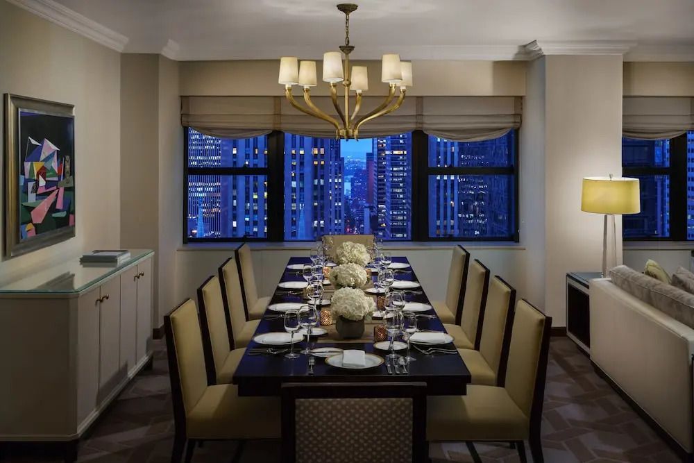 Erlesenes Esszimmer mit großem Tisch und nächtlichem Stadtblick im Lotte New York Palace.